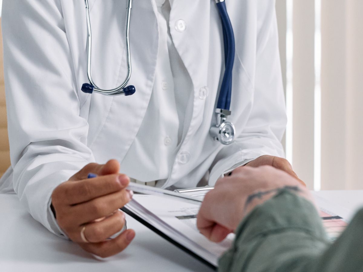 A clinician making notes on a clipboard while sitting with a patient